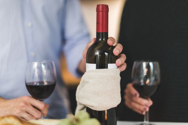 Canva Man Holding White Labeled Red Wine Bottle Near Wine Glasses