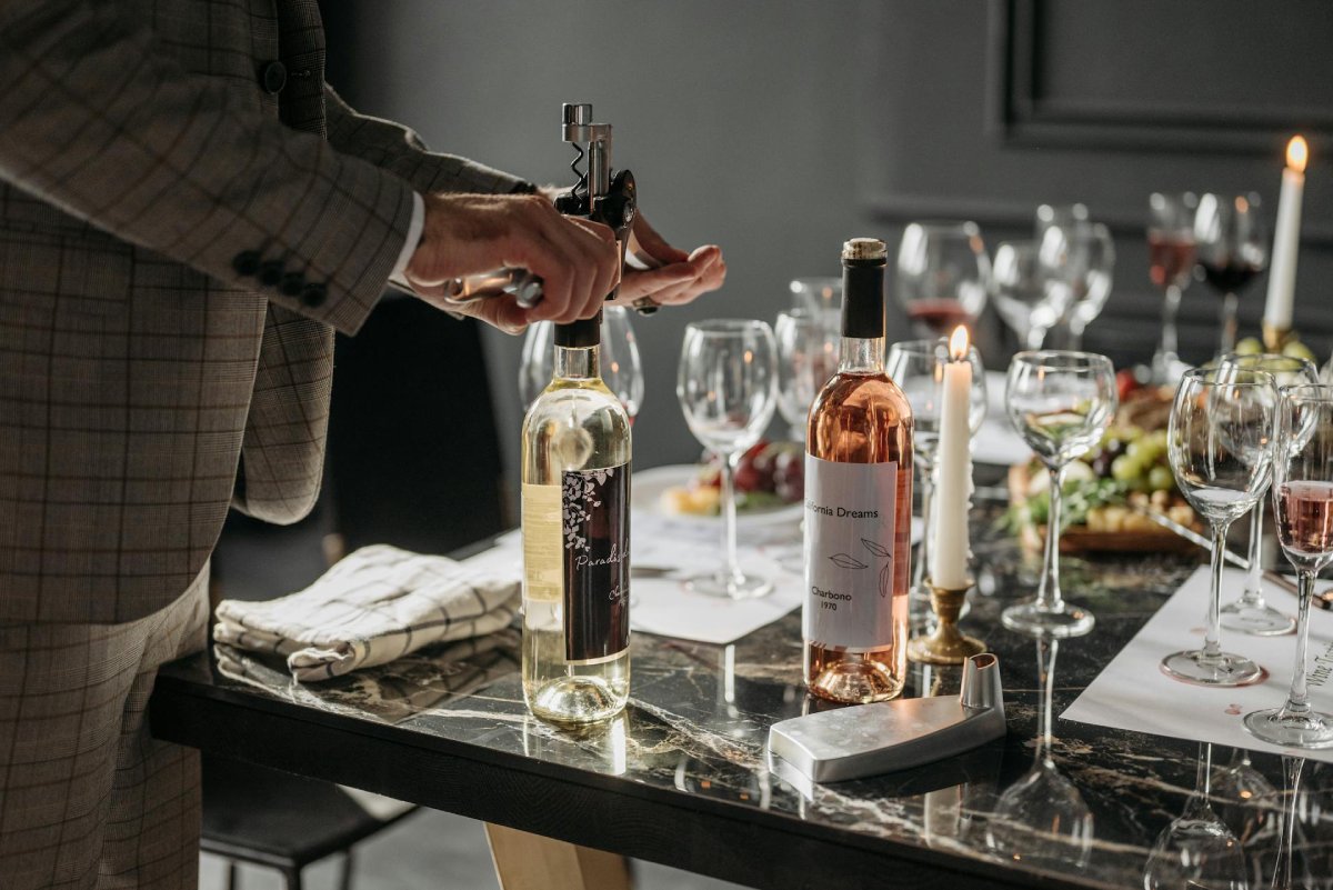 Pessoa abrindo vinho em mesa elegante para receber em casa