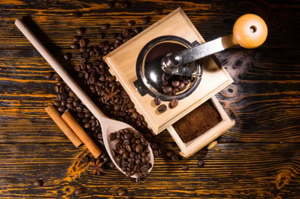 Grãos de café, café moído e moedor manual sobre uma mesa