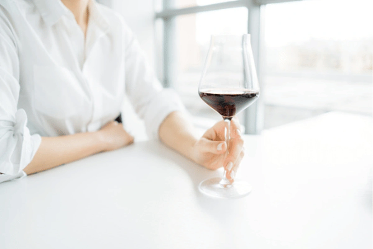Pessoa adulta degustando Aigle Royal Grande Cuvée em taça de vinho tinto