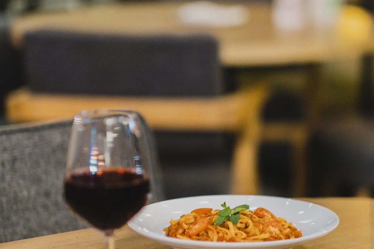 Harmonização de Angelica Zapata Merlot 2021 com pasta e taça de vinho tinto, na tonalidade indicada pela ficha