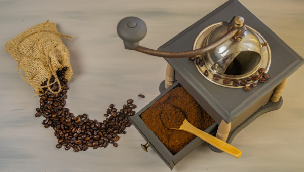 Café em grãos e café moído ao lado de um moedor