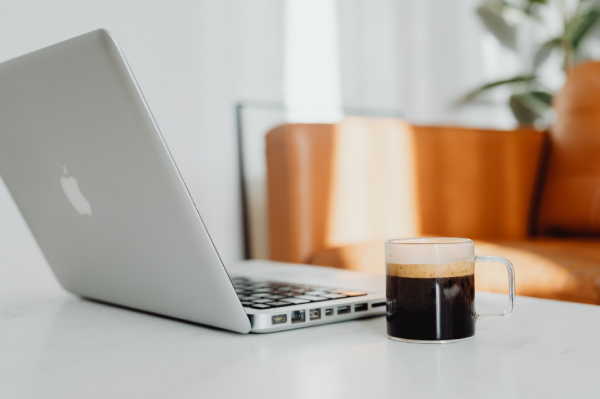 Xícara de café individual ao lado de notebook e itens de viagem