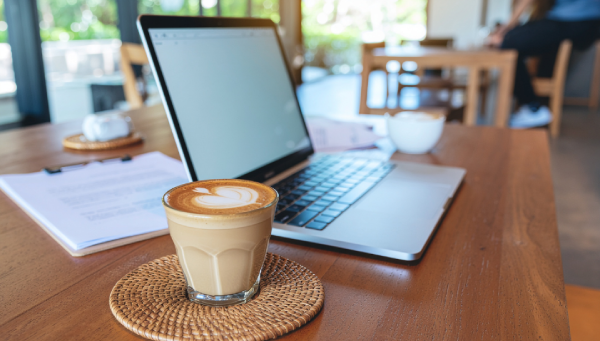 Xícara de café individual ao lado de notebook e itens de viagem