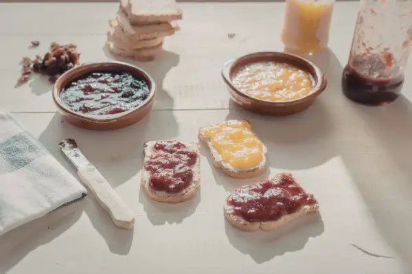 Geleia, mel, pão, frutas e castanhas em pequenas porções