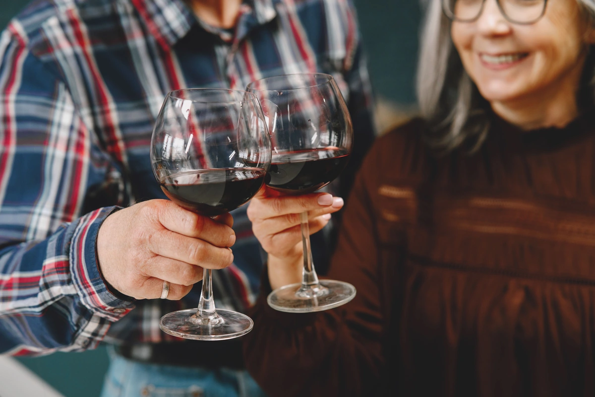 Duas pessoas brindando com taças de vinho tinto