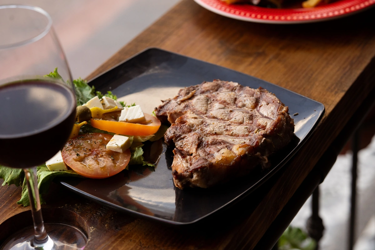 Carne grelhada e salada com taça de vinho tinto