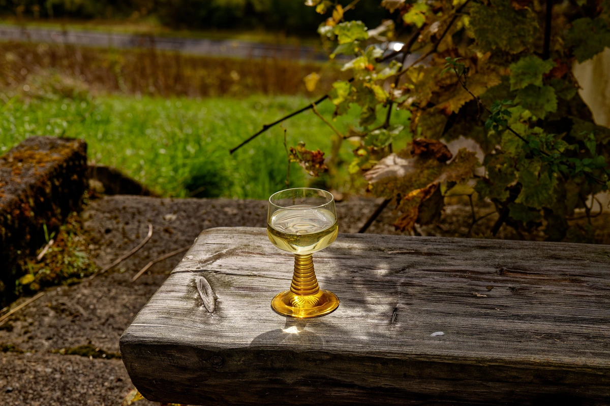 Taça de vinho branco sobre mesa de madeira ao ar livre