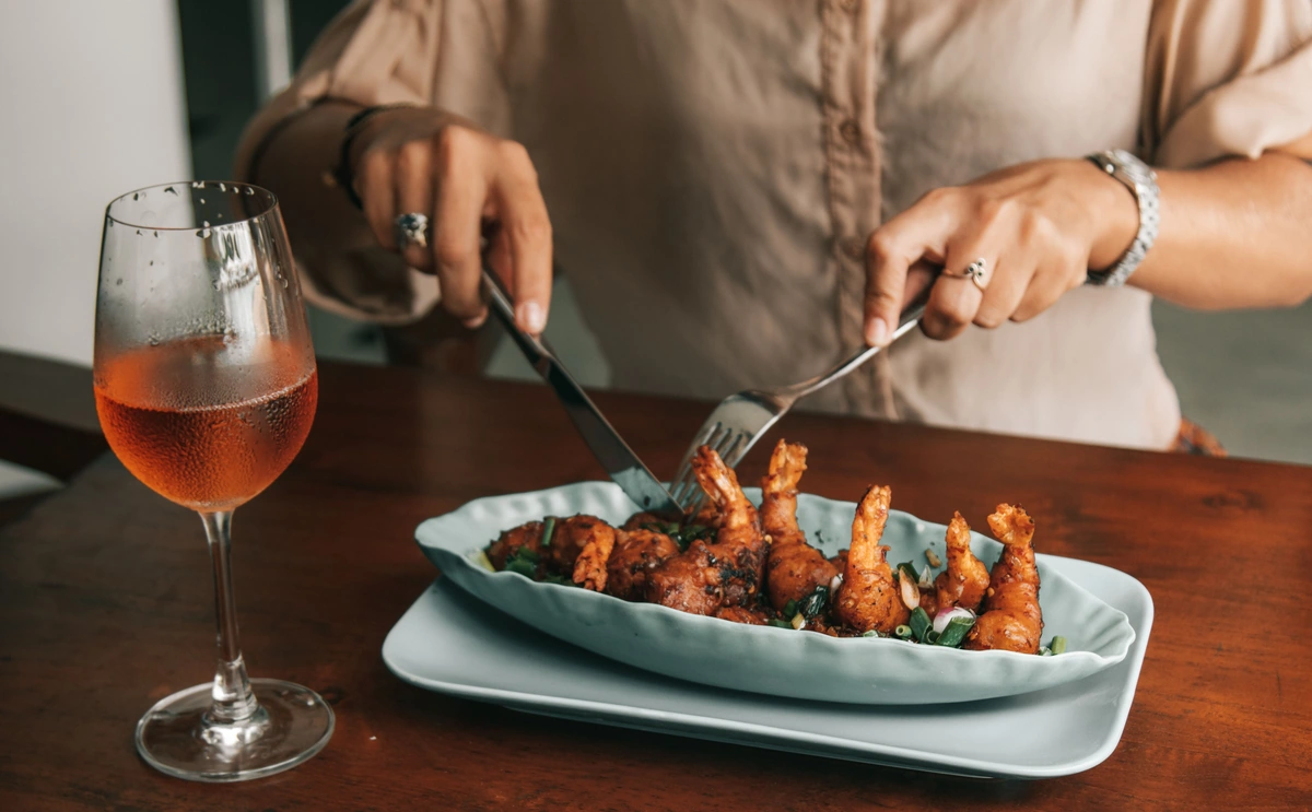 Prato de camarões com taça preenchida de rosé à mesa