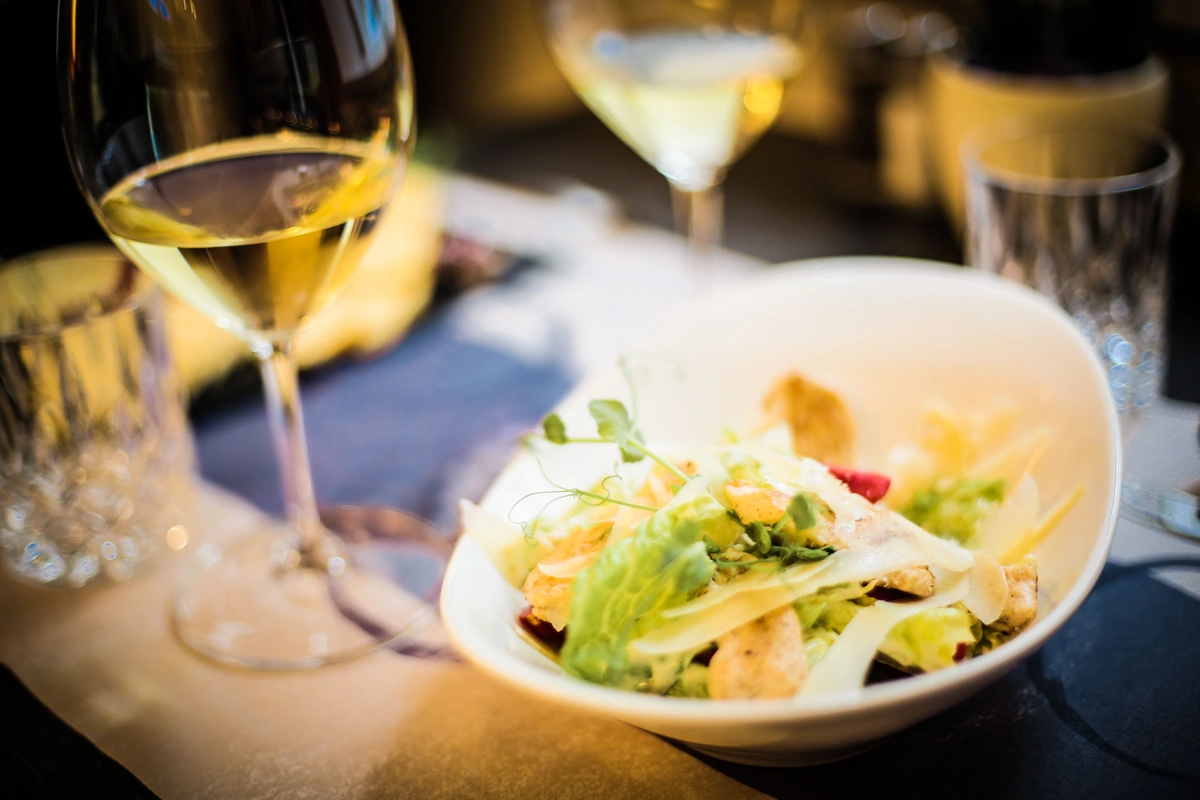 Salada com taças de vinho branco à mesa