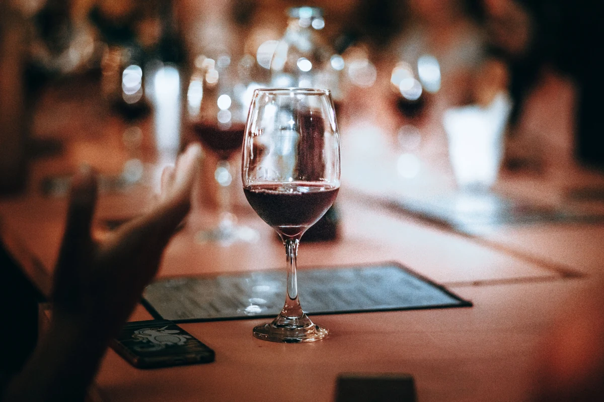 Taça de vinho tinto em primeiro plano numa mesa de restaurante.