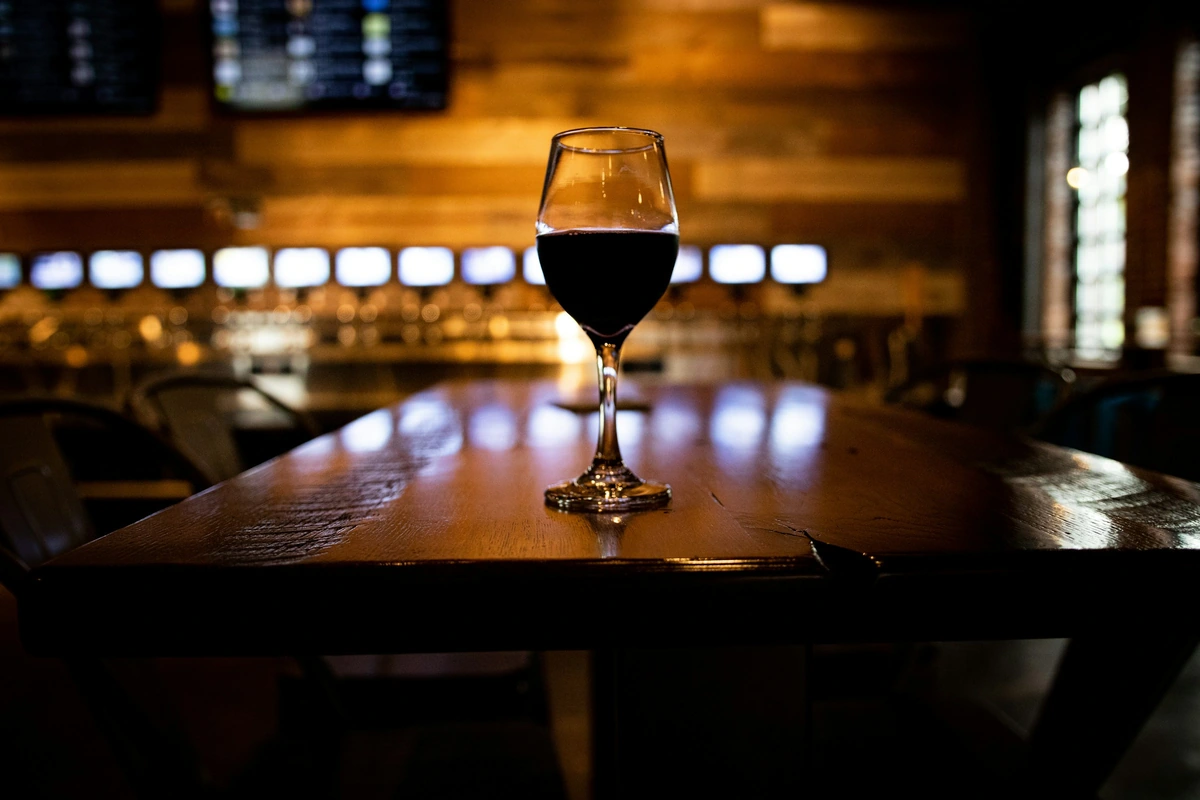 Taça de vinho tinto sobre madeira escura em iluminação quente