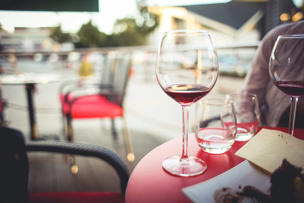 Taça de vinho tinto rubi em uma mesa externa de café à luz do dia