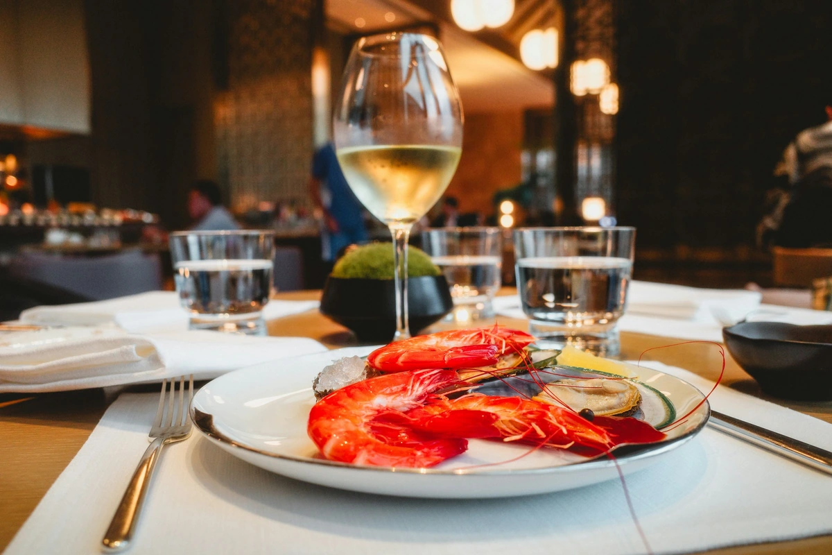 Frutos do mar servidos à mesa com uma taça de vinho branco