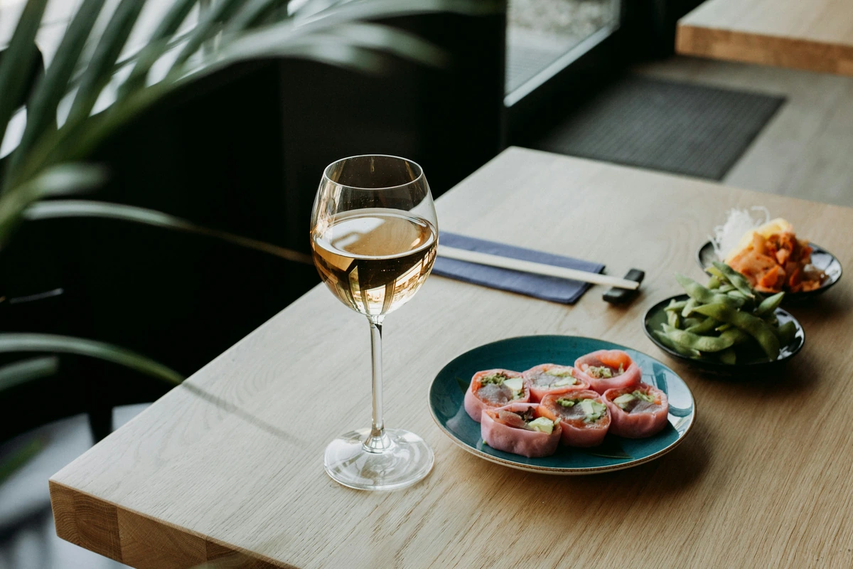 Aperitivos em pequenos pratos, vegetais e uma taça preenchida de bebida clara.