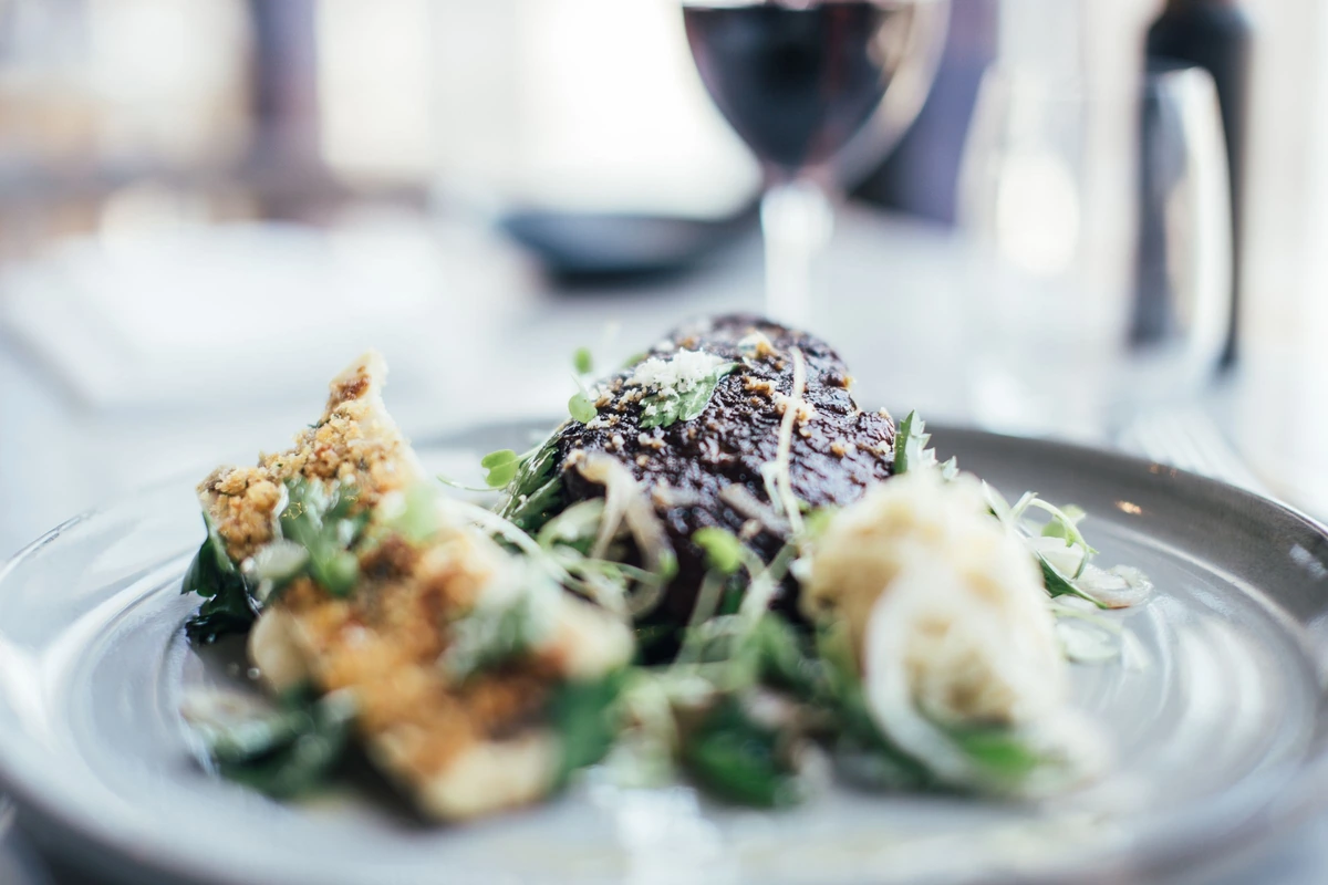 Prato com carne e vegetais acompanhado de vinho tinto