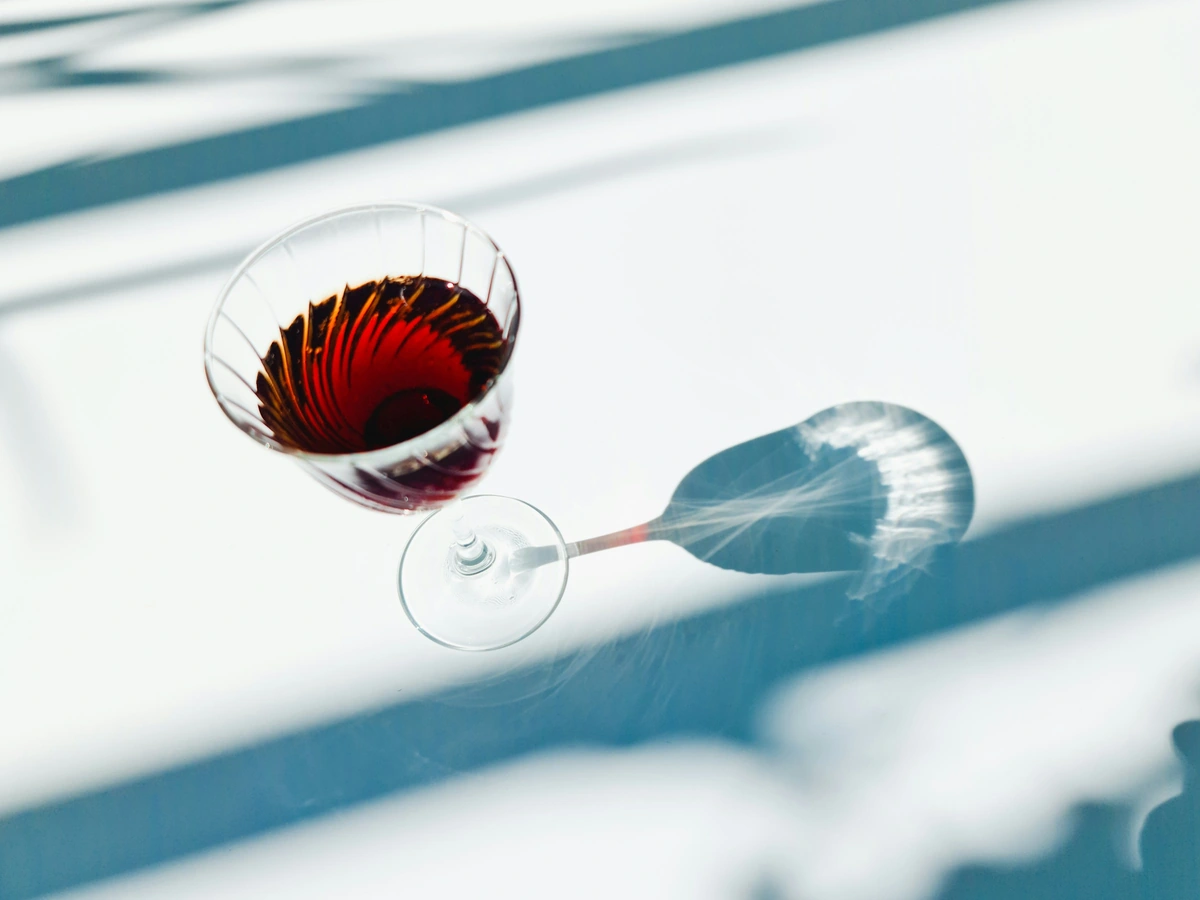 Taça de cristal com vinho tinto rubi translúcido sobre mesa branca