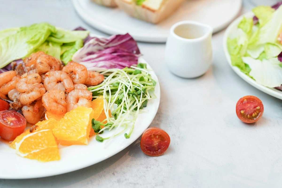 Salada de camarões com folhas, tomates e cítricos em mesa clara