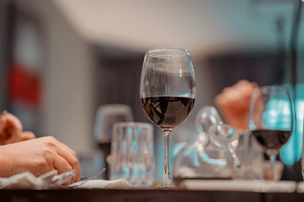 Taça de vinho tinto em foco sobre a mesa de uma refeição