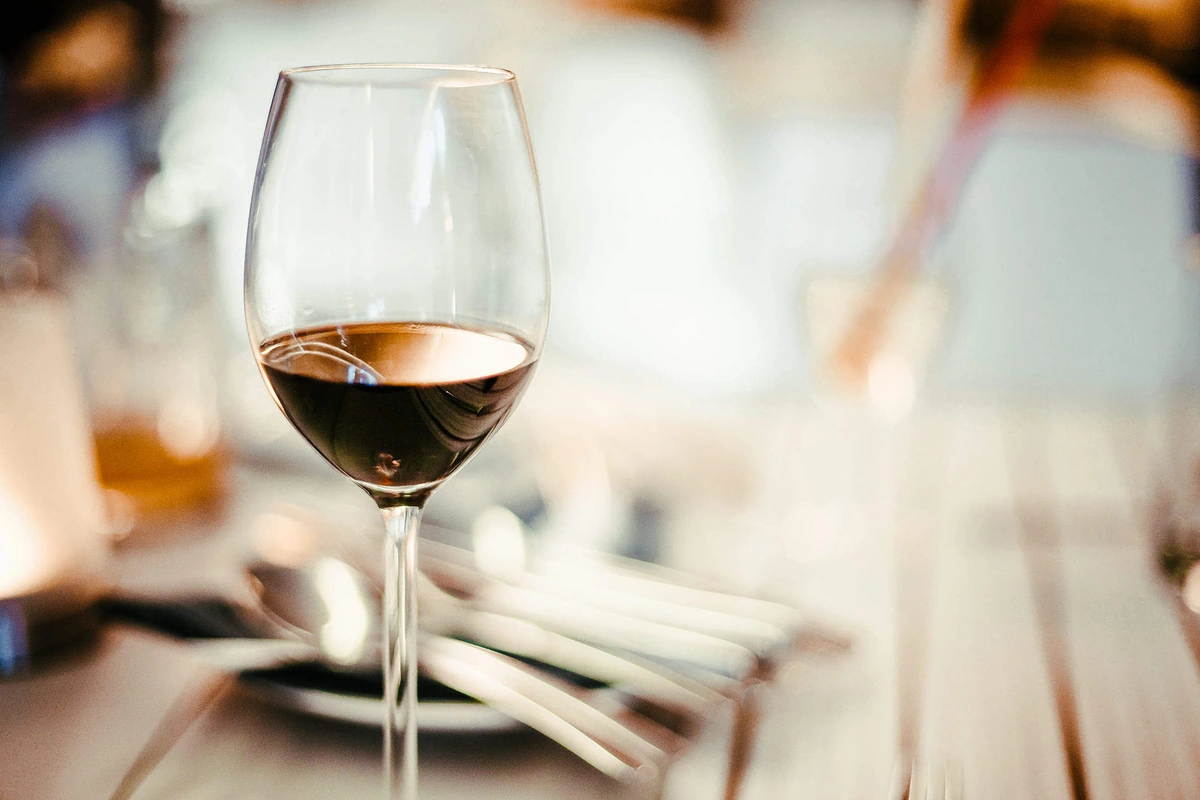 Taça de vinho tinto em primeiro plano em restaurante com iluminação quente