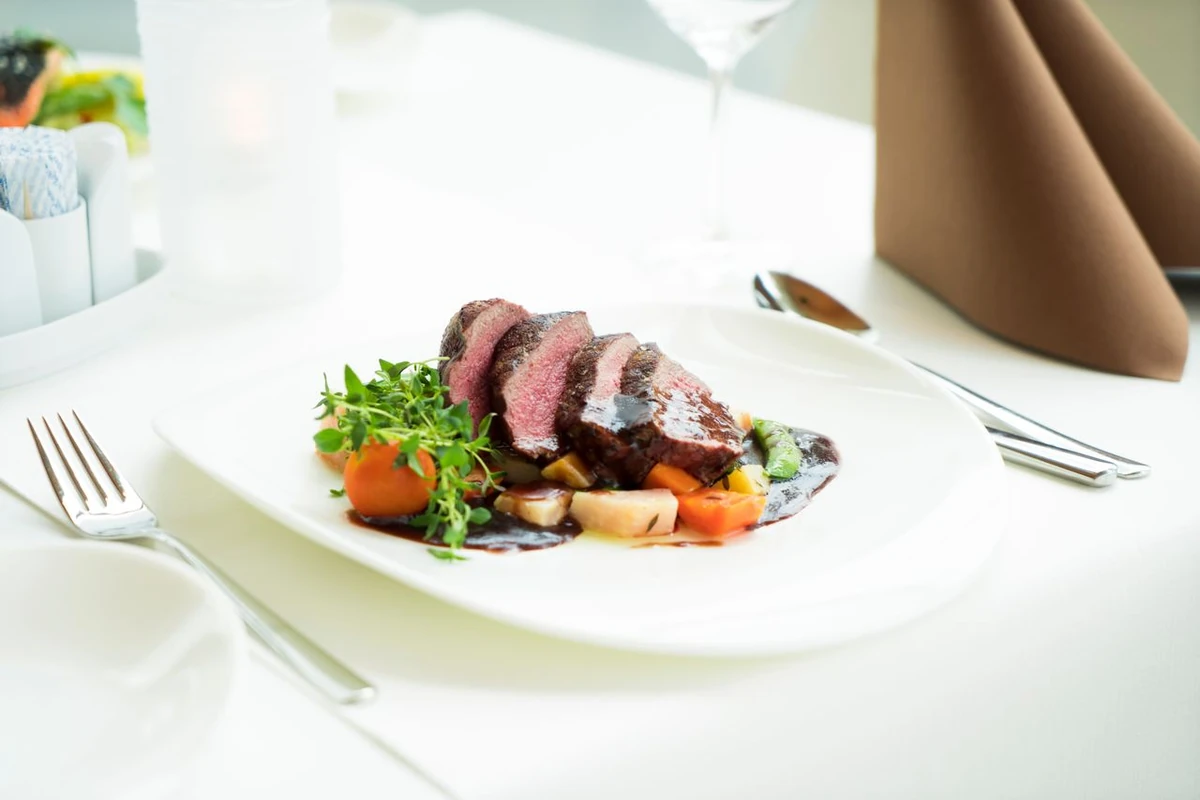 Carne fatiada com ervas e legumes em prato branco
