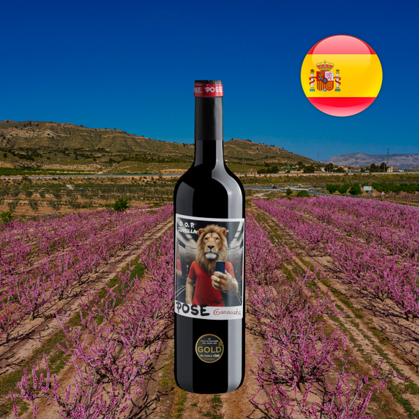 Garrafa de Pose Garnacha Jumilla diante de um campo florido e colinas, com bandeira da Espanha.