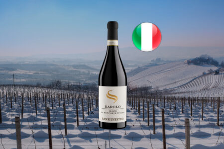 San Silvestro Barolo DOCG del Comune di Monforte d’Alba em garrafa inteira, com rótulo branco, sobre paisagem horizontal de colinas e vinhedos nevados do Piemonte, com bandeira italiana.