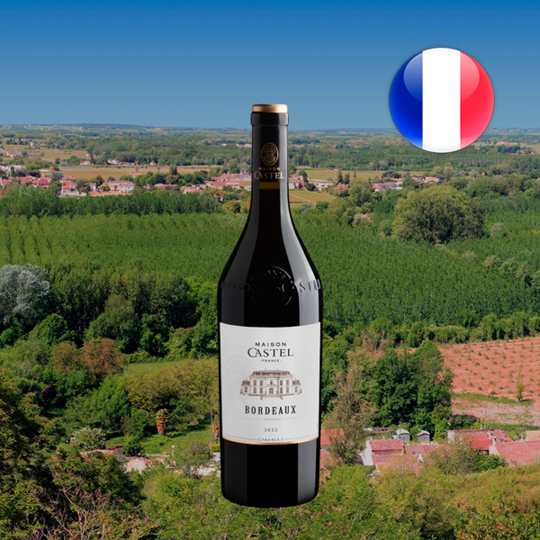 Garrafa de Maison Castel Bordeaux 2023 diante de vinhedos e construções, com bandeira da França.