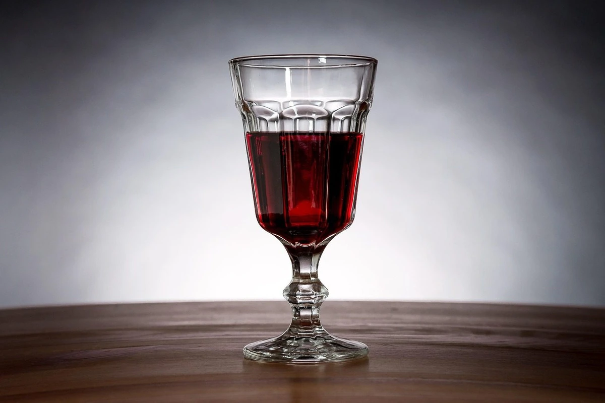 Taça trabalhada com vinho tinto sobre madeira