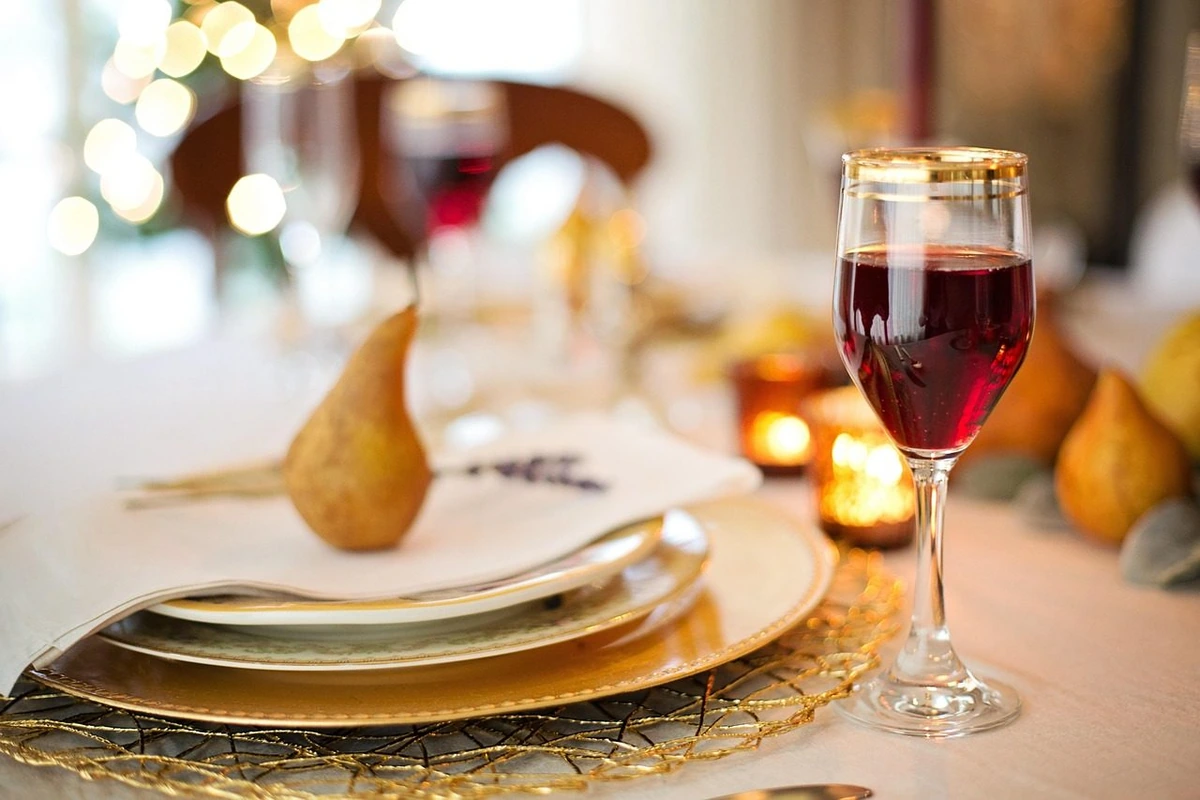 Taça de tinto rubi sobre mesa posta com louça e velas