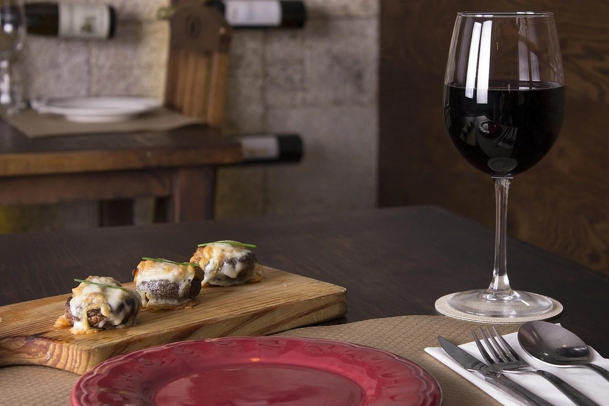Cogumelos recheados com queijo junto de uma taça de tinto