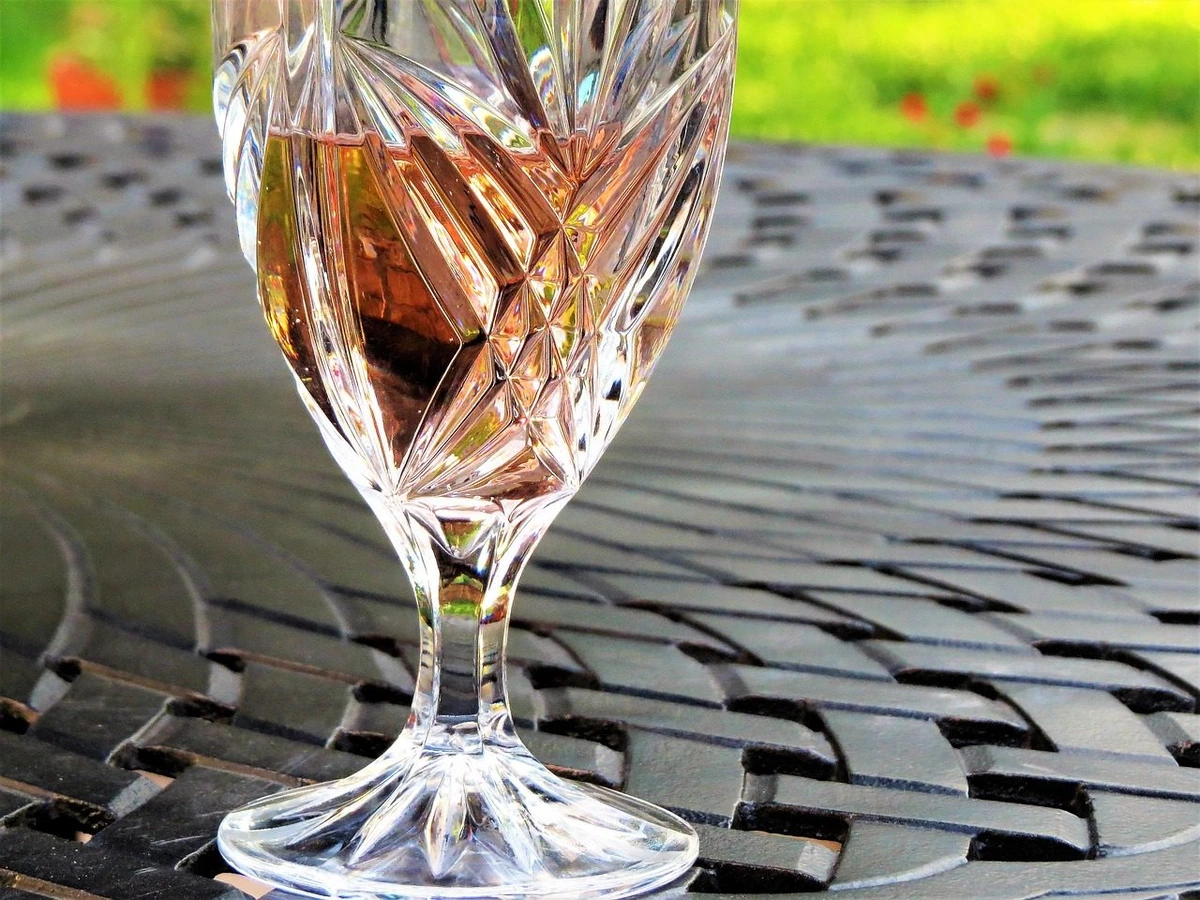 Taça preenchida com vinho rosé sobre mesa ao ar livre