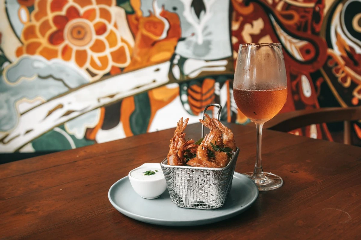 Camarões empanados com molho e taça de vinho em mesa de restaurante