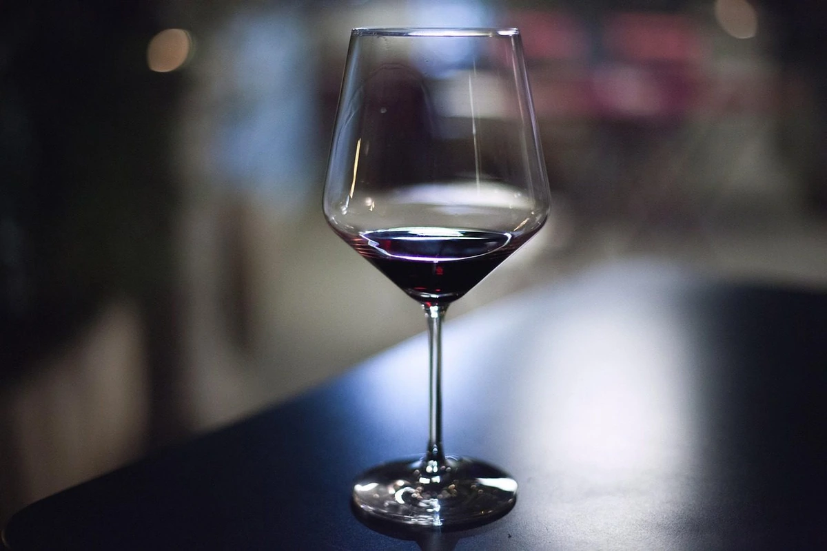 Taça de vinho tinto sobre mesa de madeira escura